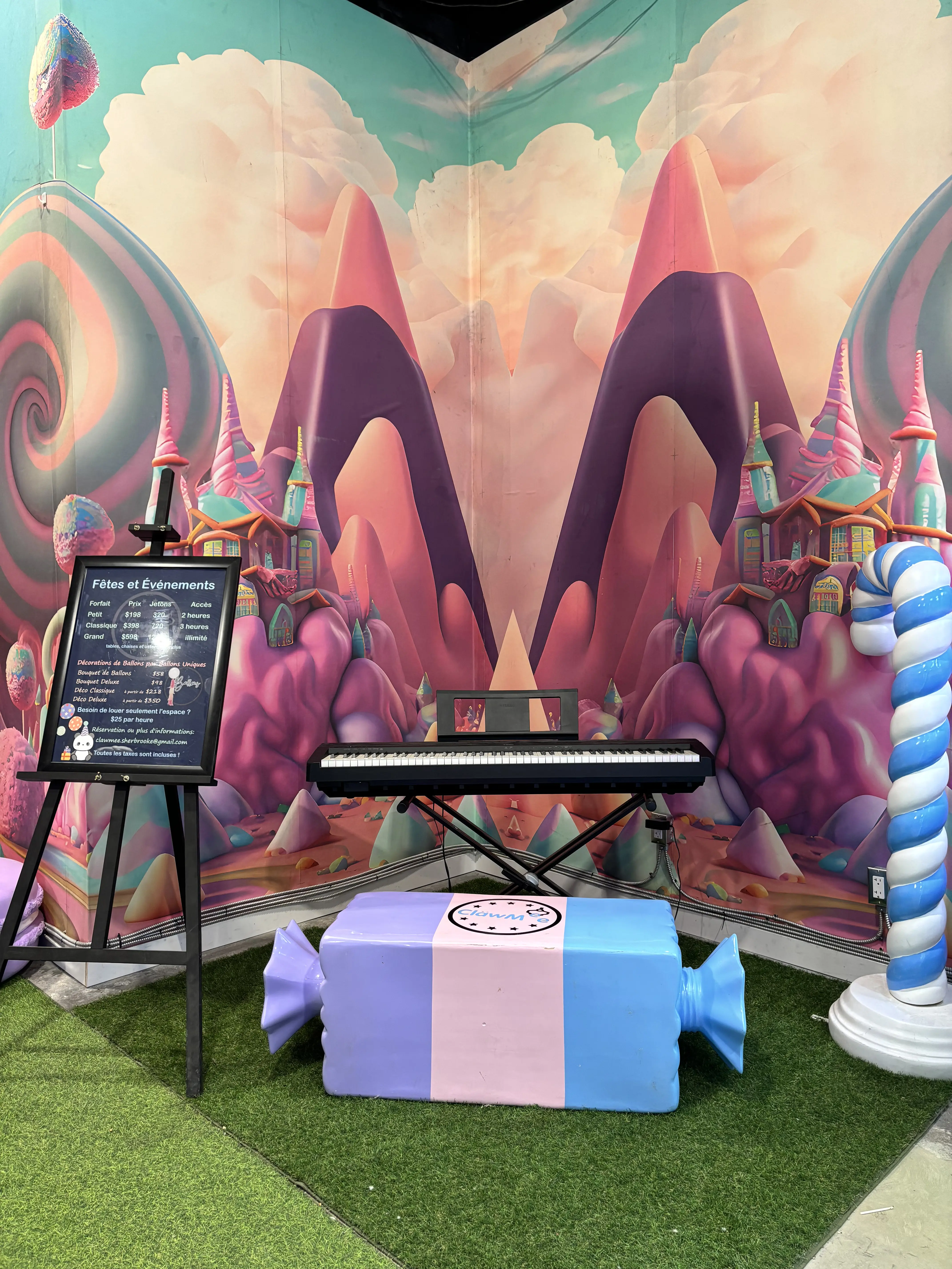 Candyland corner with a piano and candy-shaped bench in front of the candy-mountain mural
