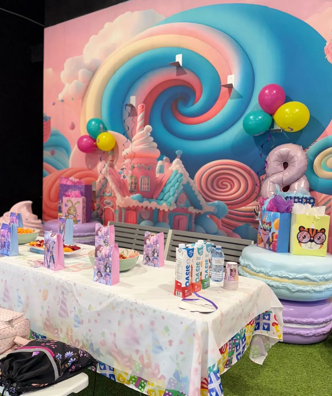 Birthday table set with treat bags, fruit and drinks in front of the candy mural
