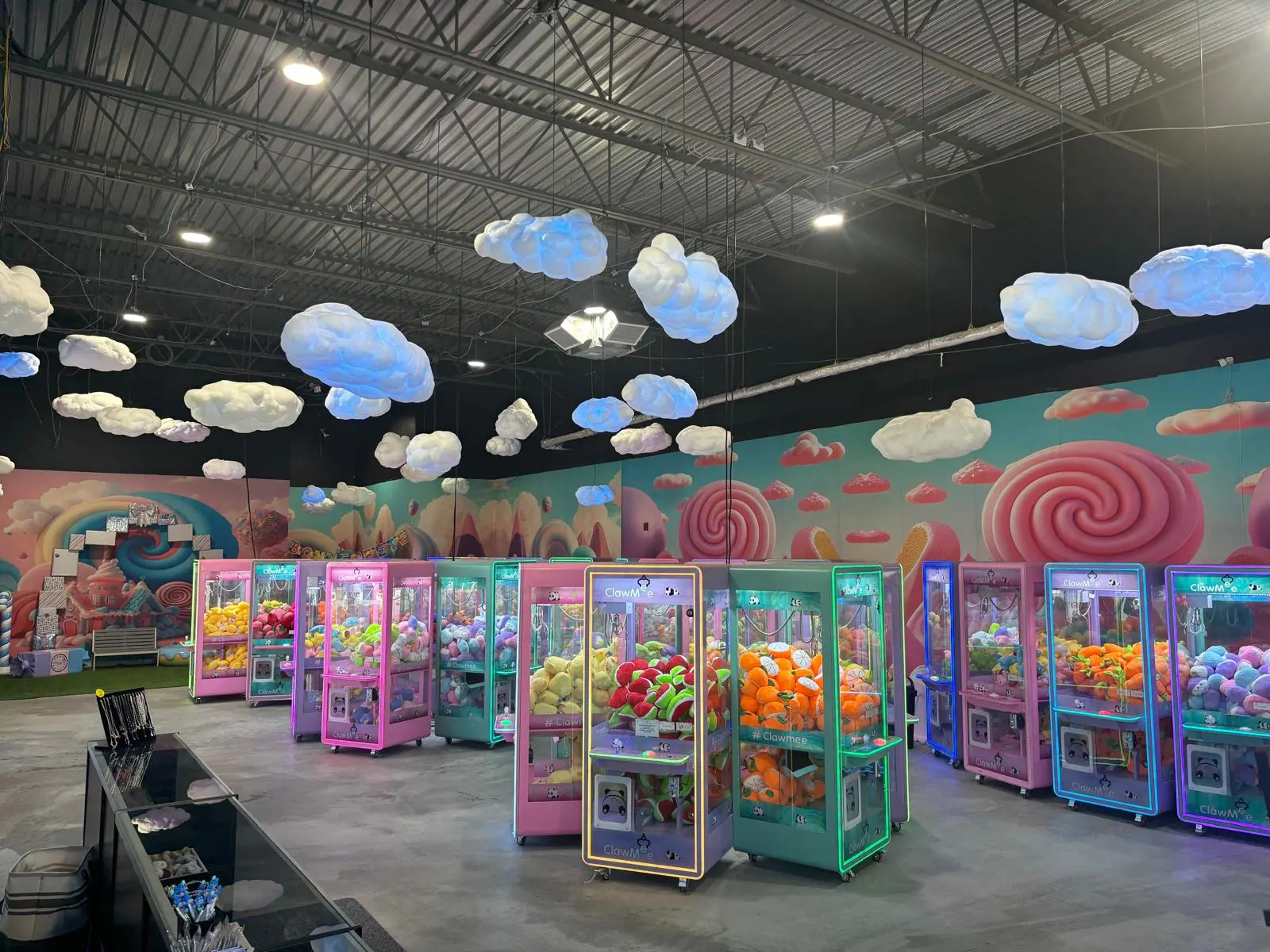 Inside ClawMee Sherbrooke: rows of colourful claw machines and glowing clouds on the ceiling