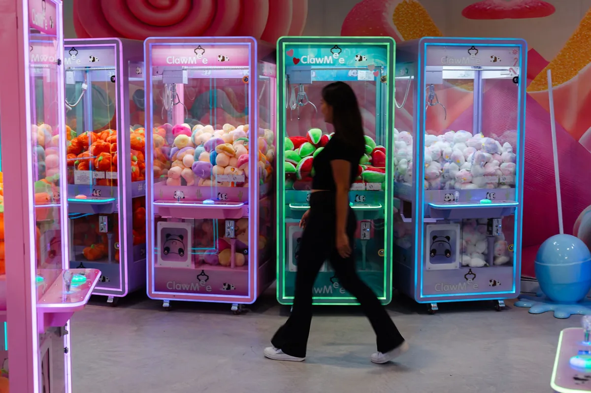 Row of colourful claw machines full of plushies